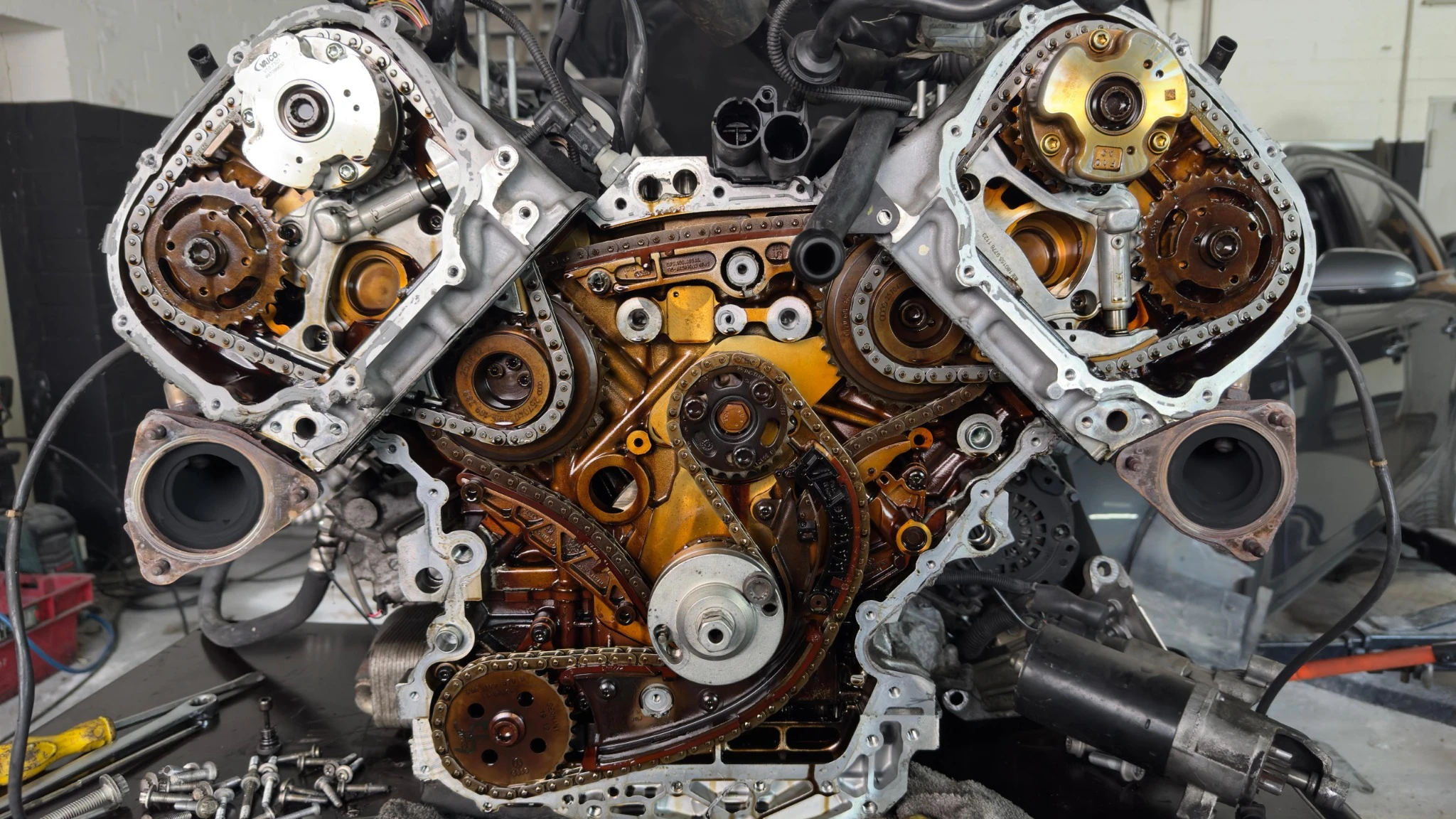 Kompletter freigelegter Steuerkettentrieb eines V6-Motors vor dem Steuerkettenwechsel mit sichtbaren Ketten, Zahnrädern und Spannern