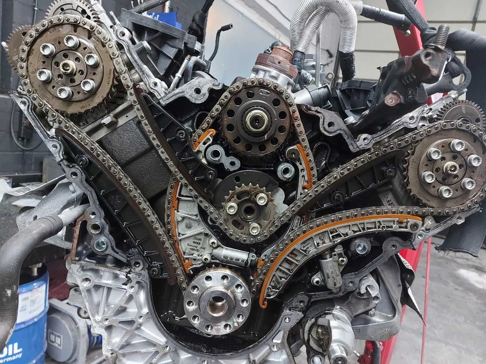 Geöffneter Steuerkettentrieb eines modernen V6-Motors mit mehreren Steuerketten, Zahnrädern, Gleitschienen und Kettenspannern während der Reparatur