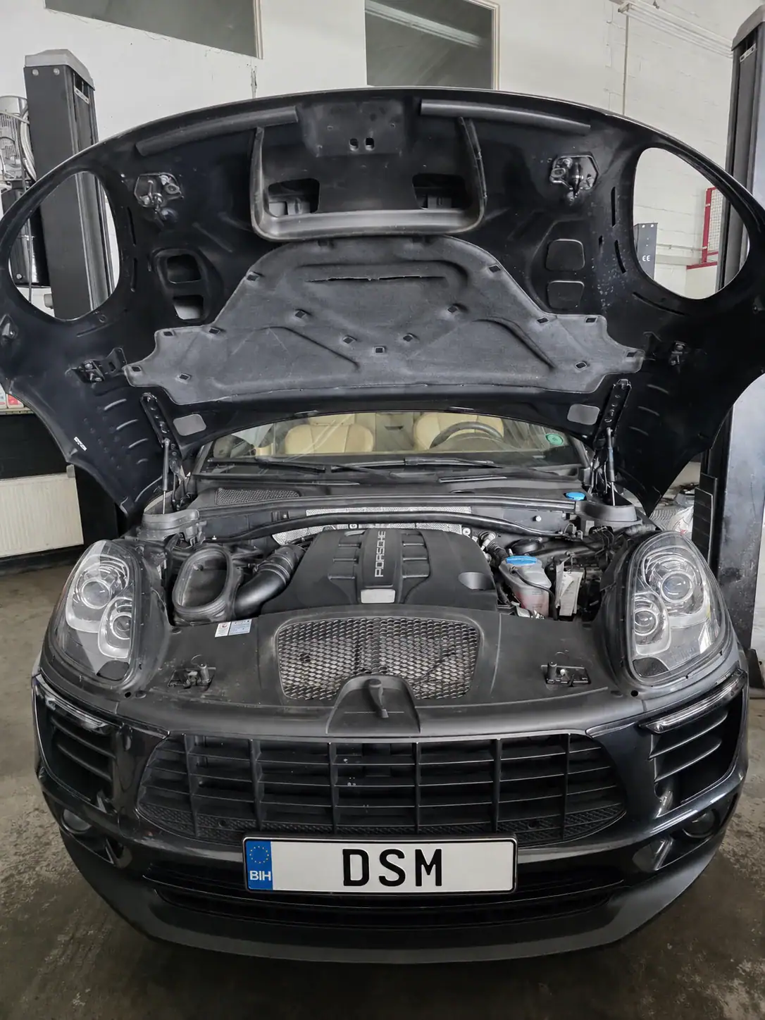 Porsche Macan mit geöffneter Motorhaube in der Werkstatt von DSM Motorinstandsetzung